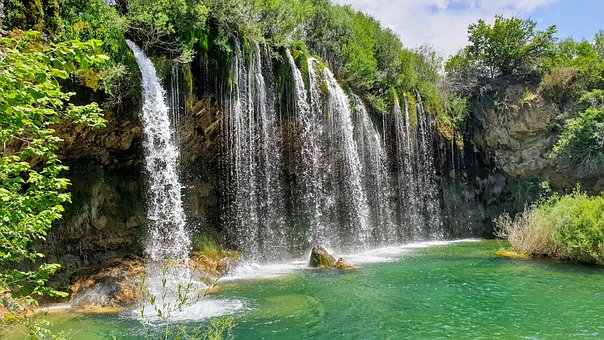 Water falls from a waterfall with some gravitational potential energy